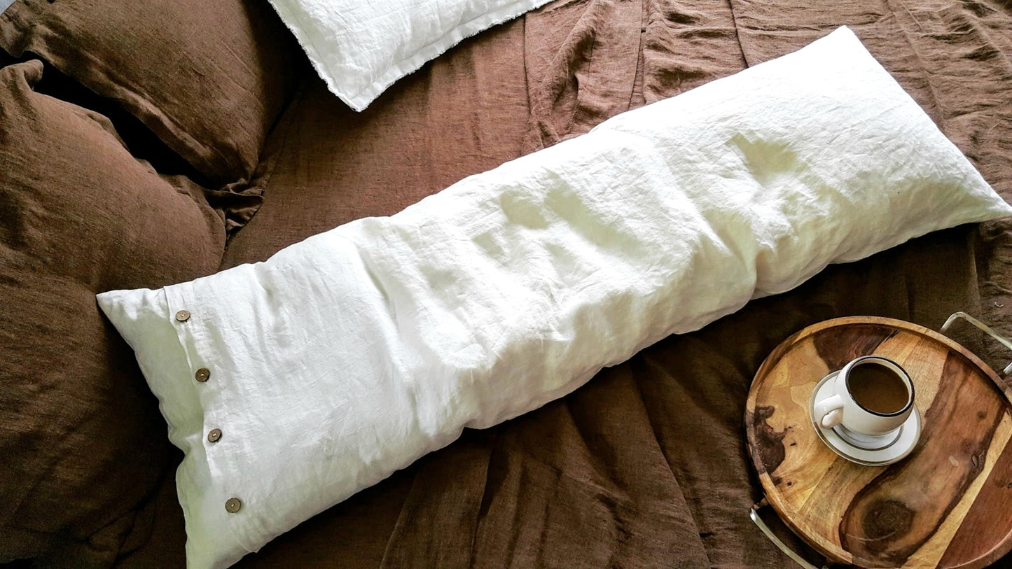 White linen pillow cover with buttons on the bed with brown linen sheet 